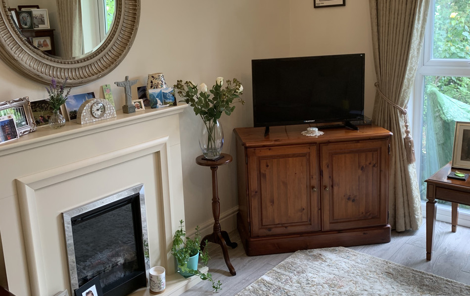 An Abbeyfield residents cosy living room with traditional fireplace and television