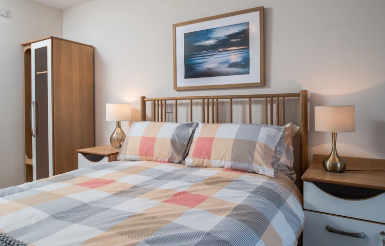 Double bed with a checkered bedspread and bedside cabinets at Hope Bank View