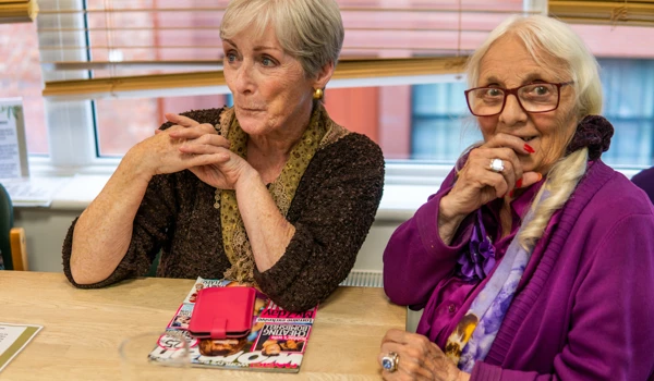 Two Older Women Sitting Together At Table Happily