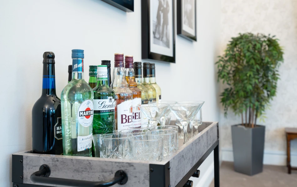Assorted bottles of spirits and wine on a drinks trolley with glassware at Westall House Residential Care Home in Horsted Keynes.
