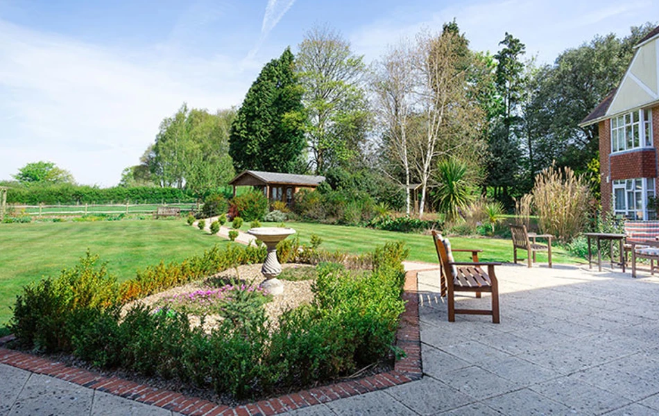 Beautiful expansive garden at Westall House, with paved patio and seating area and a variety of plants and trees