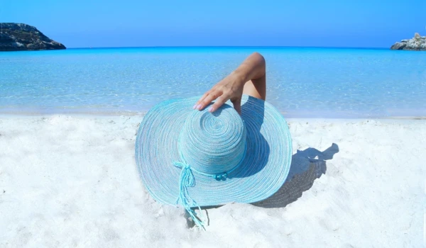 Woman Holding Sunhat Lying On The Beach
