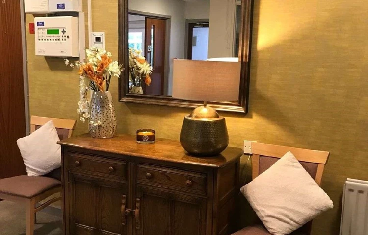 A desk and chairs in the entrance with a lamp