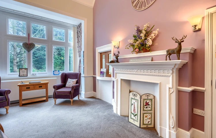 Interior of Westall House Residential Care Home sitting room with fireplace, armchairs, and large window.