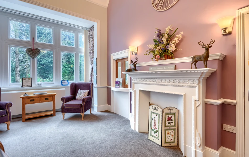 Interior of Westall House Residential Care Home sitting room with fireplace, armchairs, and large window.