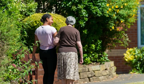 Staff Member And Resident Walking In The Garden