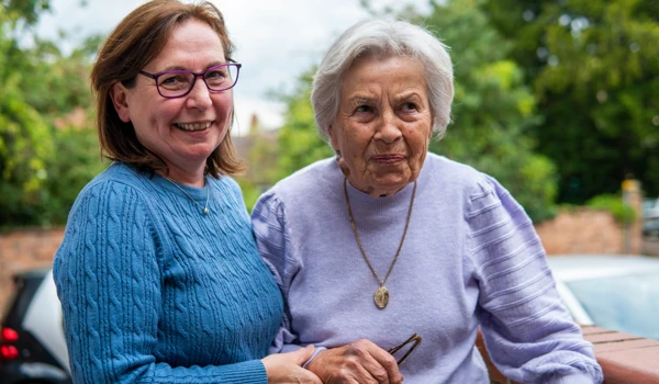 Older Woman Being Supported By Woman Whilst Walking