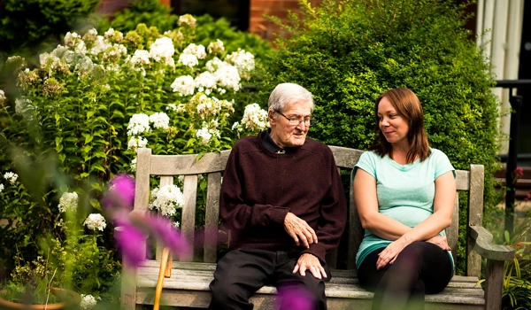 Older Man Sitting On Bench With Younger Woman