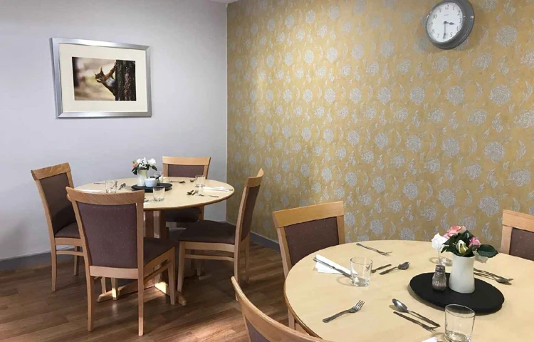 The dining area with table and chairs and yellow flowered wall