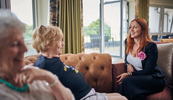 Happy Residents And Staff Sitting Together On Sofas In A Lounge