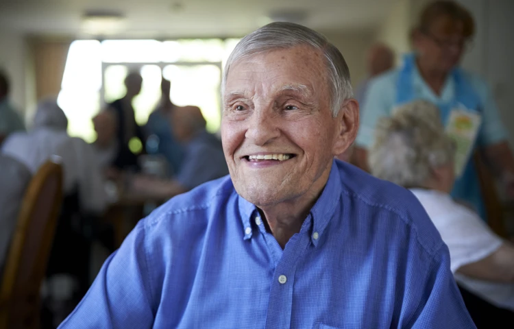 Smiling, happy resident sitting in the communal dining room at Westall House Residential Care Home.