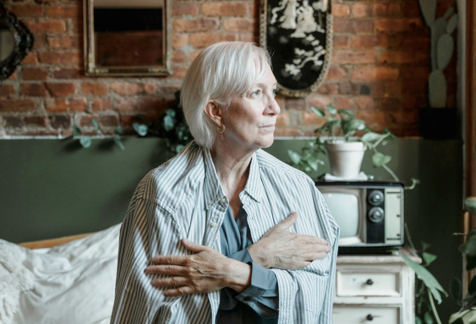 Older woman looking out of window with shirt wrapped around her