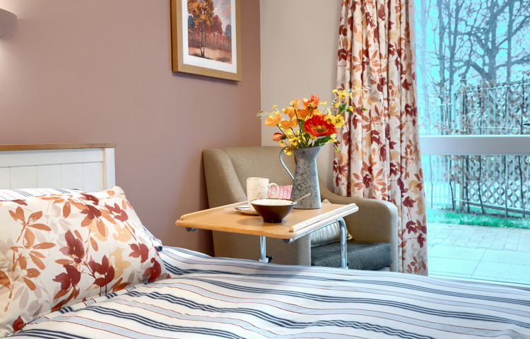 A beautifully decorated bedroom at Westall House with art, flowers and a garden view