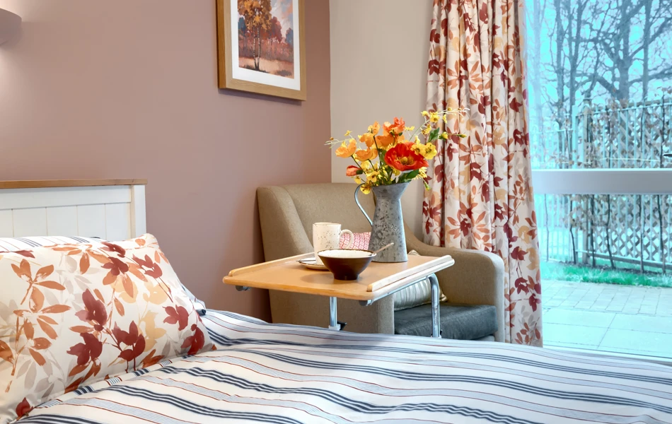 A beautifully decorated bedroom at Westall House with art, flowers and a garden view