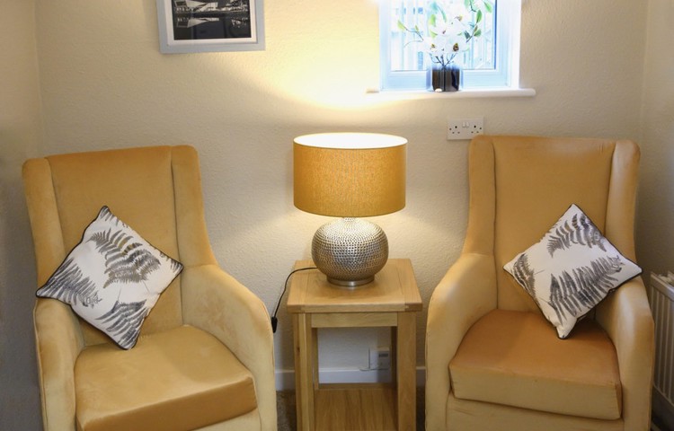 Snug area with two yellow chairs and a lit table lamp