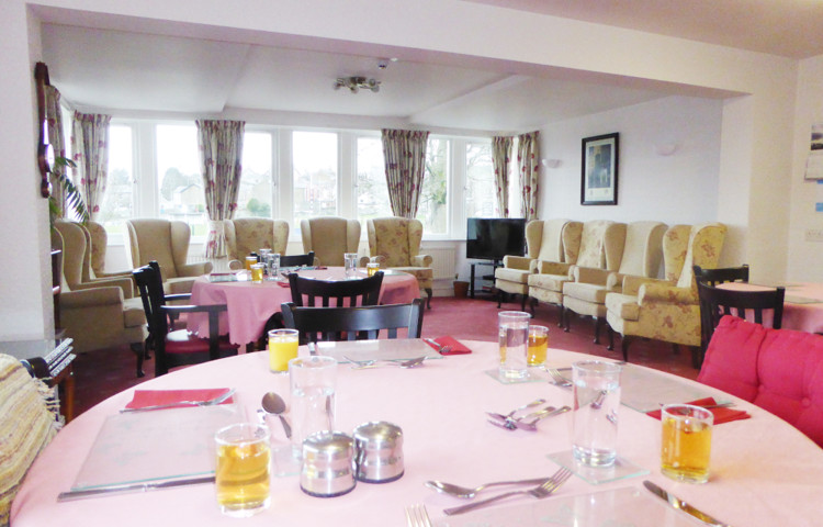 A table set for dinner with armchairs around the edge of the room