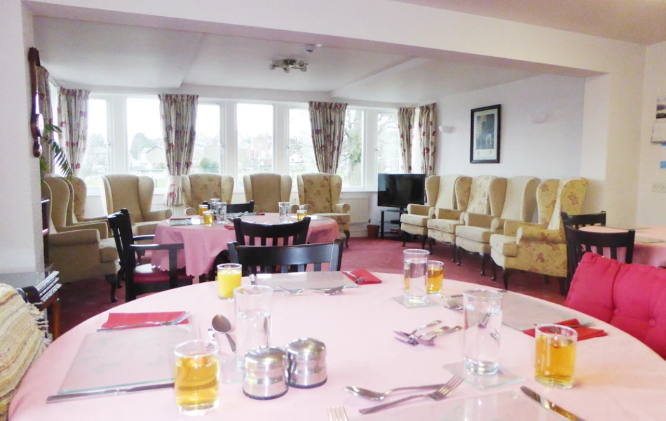 A table set for dinner with armchairs around the edge of the room