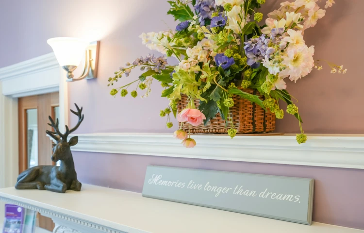Decorative details in a room at Westall House Residential Care Home in Horsted Keynes, including a floral arrangement, stag figurine, and an inspirational quote.