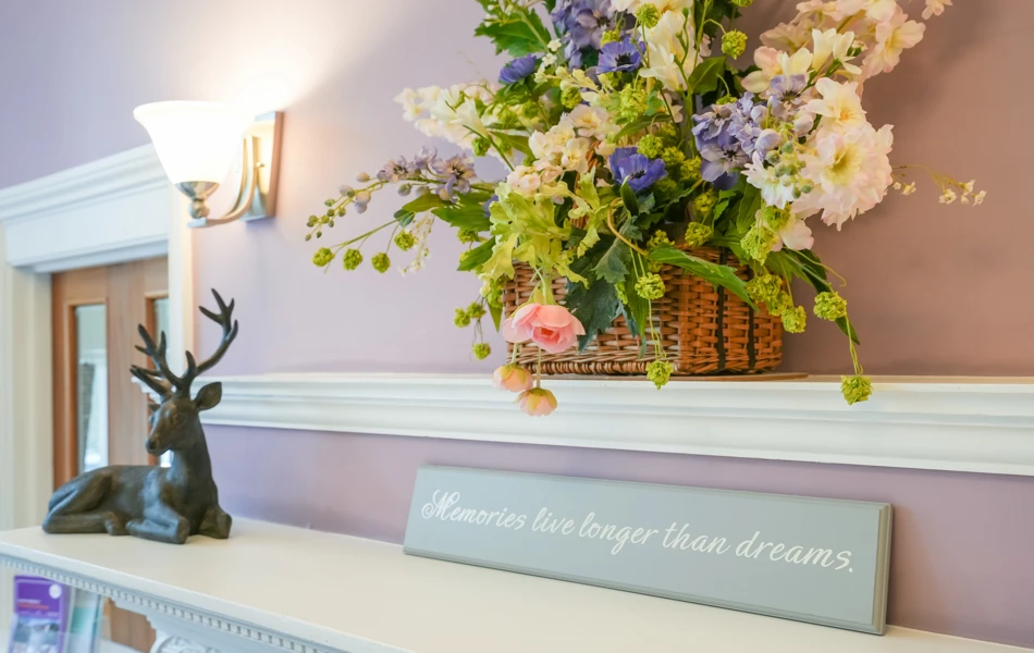 Decorative details in a room at Westall House Residential Care Home in Horsted Keynes, including a floral arrangement, stag figurine, and an inspirational quote.