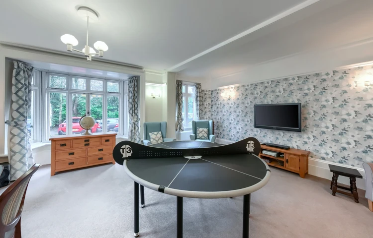 Table tennis table, comfortable armchairs, and a large television in the activity room at Westall House Residential Care Home in Horsted Keynes.